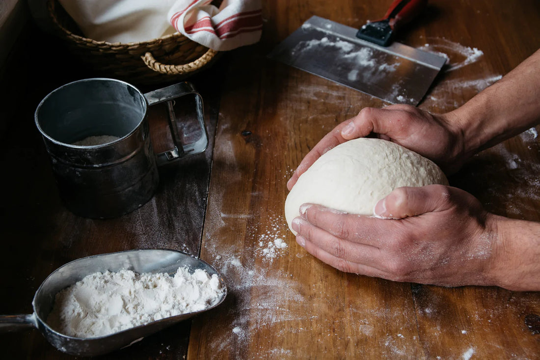 Person working dough with flour on a wooden table